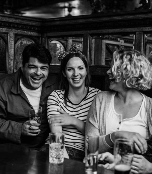 Three friends enjoying drinks and laughing together