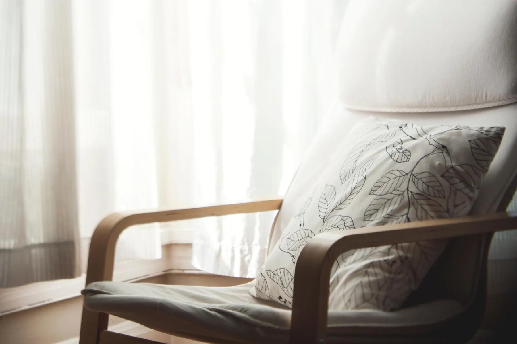 Wooden chair with decorative pillow near window
