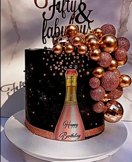 Black birthday cake with champagne bottle design and rose gold decor