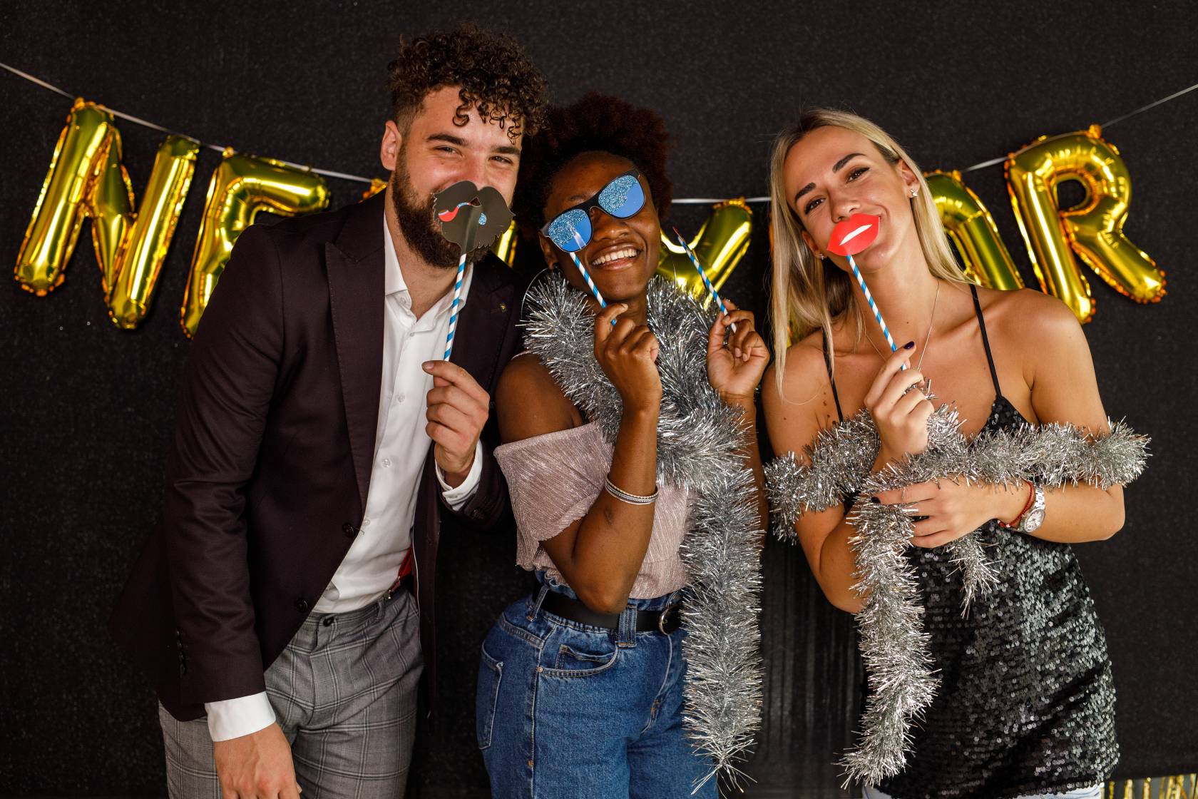 Three people with props at a New Year photo booth