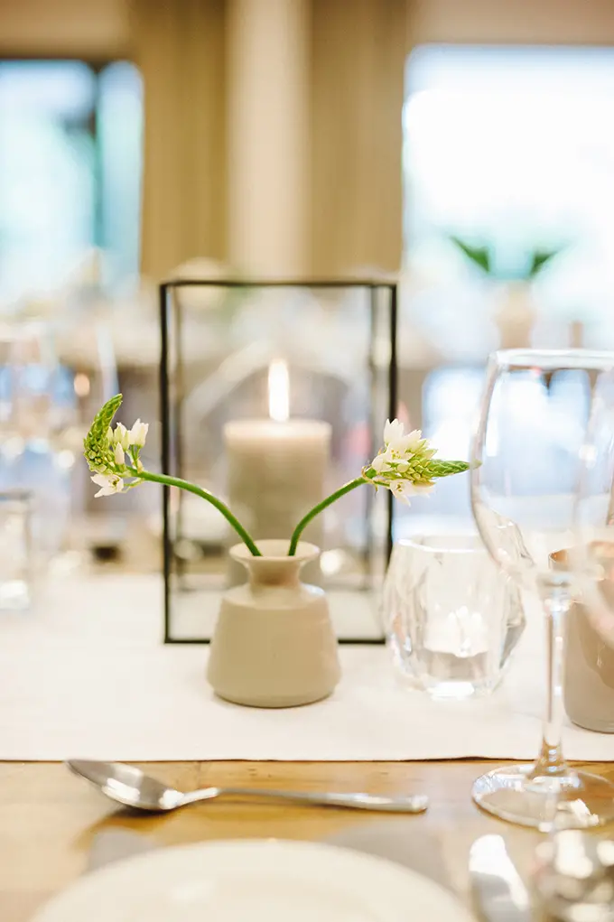 Delicate floral centerpiece with a candle and glassware on a table