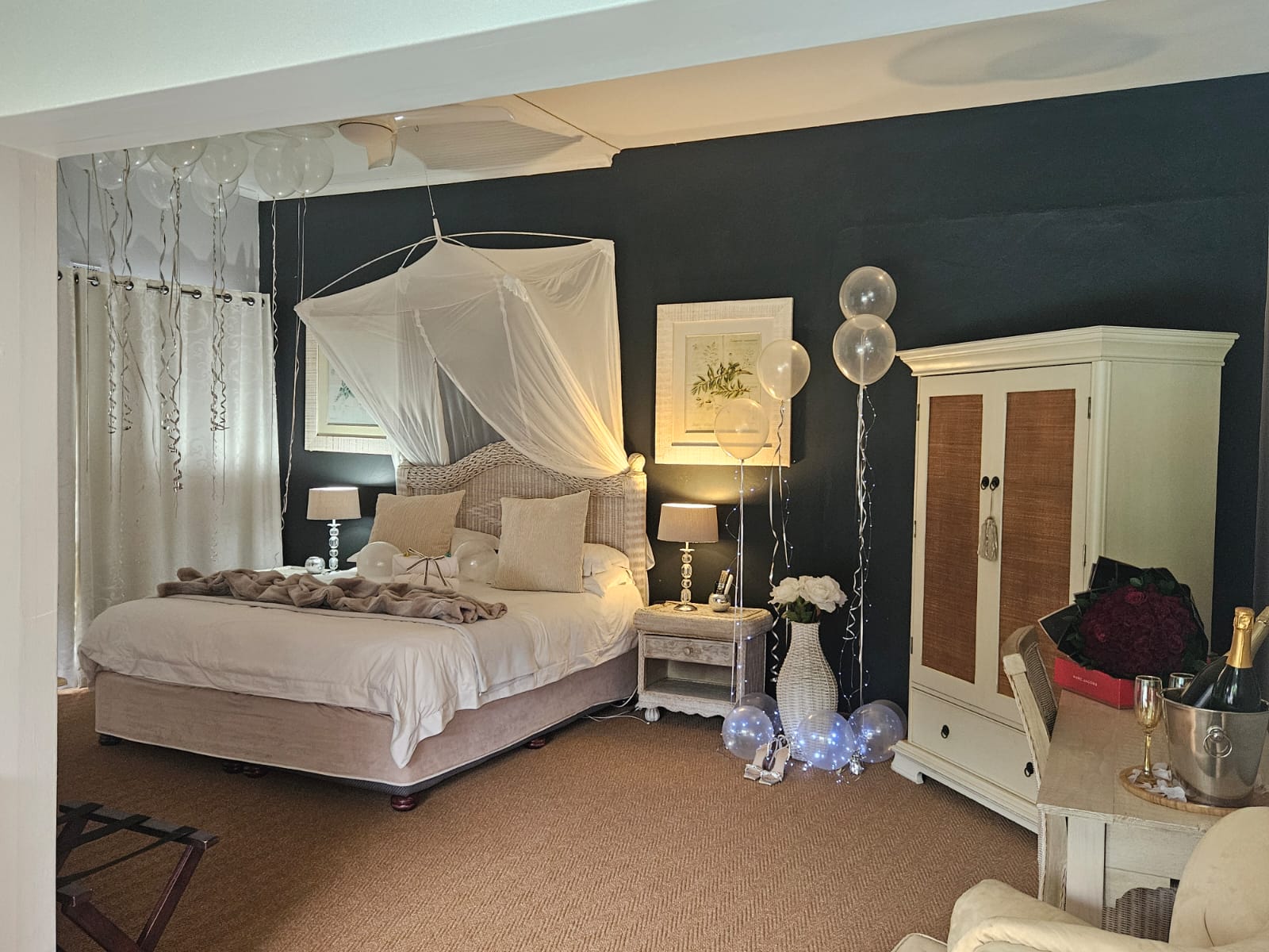 Decorated room with bed, balloons, and champagne