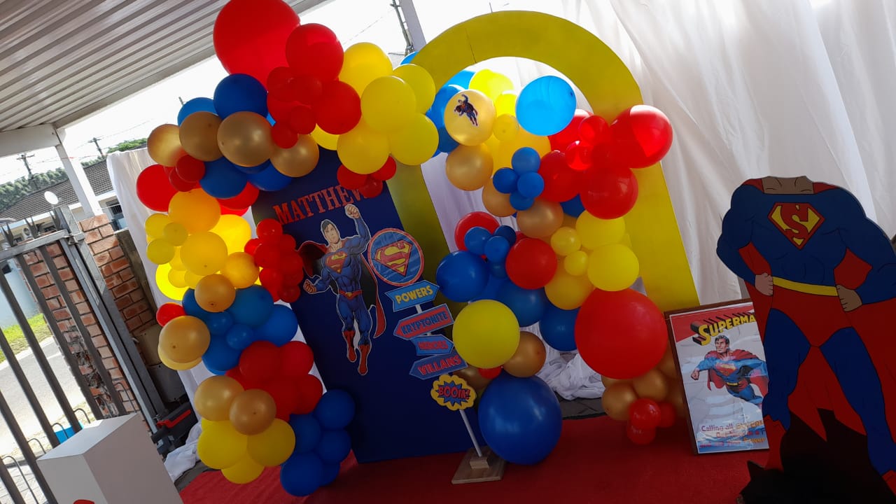 Vibrant superhero-themed balloon arch with cutouts and signage.
