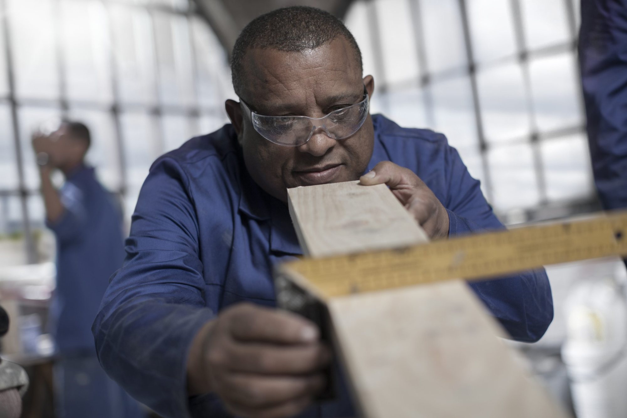 Person measuring wood with a tape measure in workshop