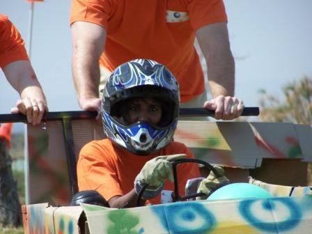 Child in a helmet participating in a soap box derby race.