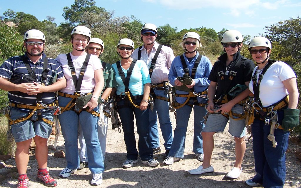 Group of people wearing safety gear for zip lining activity.