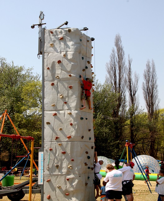 Participant climbing a rock wall at an outdoor team building event.