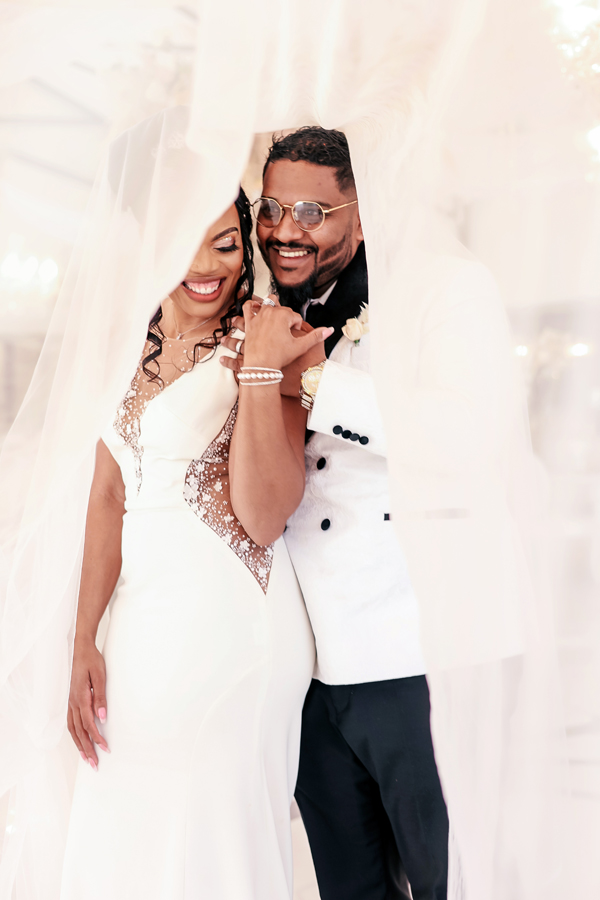 Couple smiling together under a wedding veil