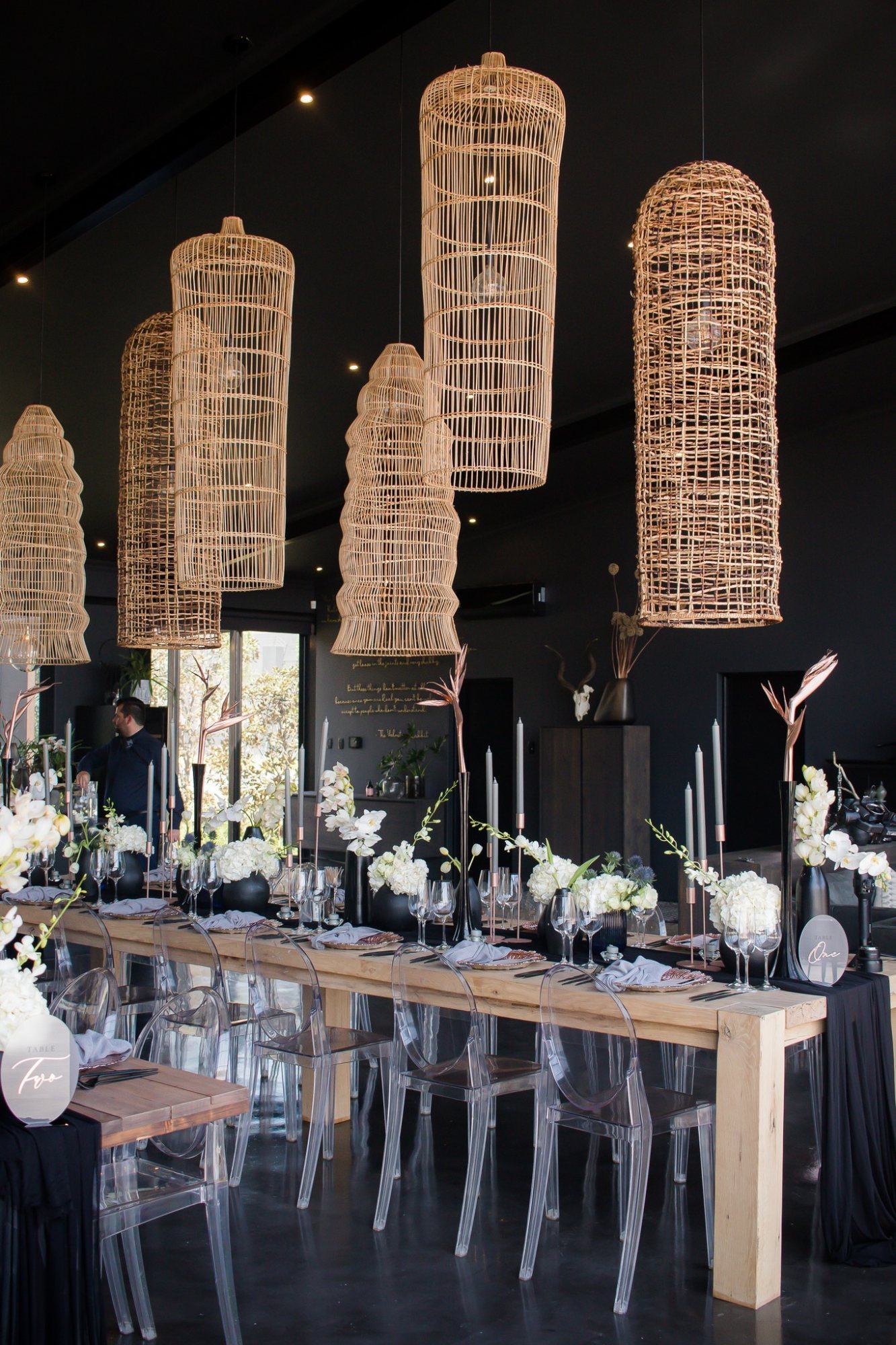 Elegant event space with woven pendant lights and floral decor