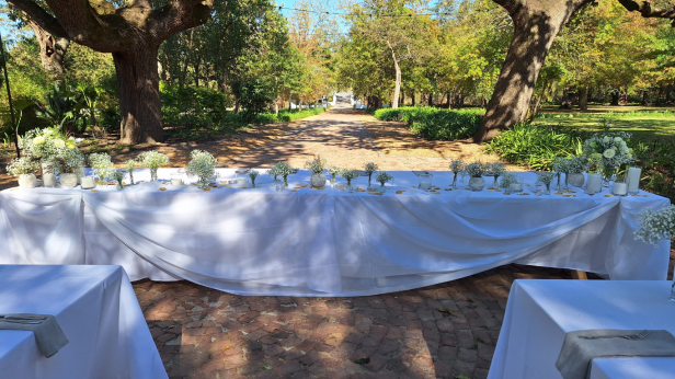 Outdoor table setup with floral decor and white tablecloth