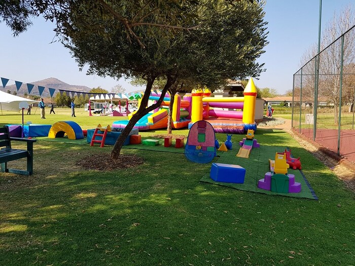 Outdoor kiddies soft play area with inflatable castle and colorful toys.