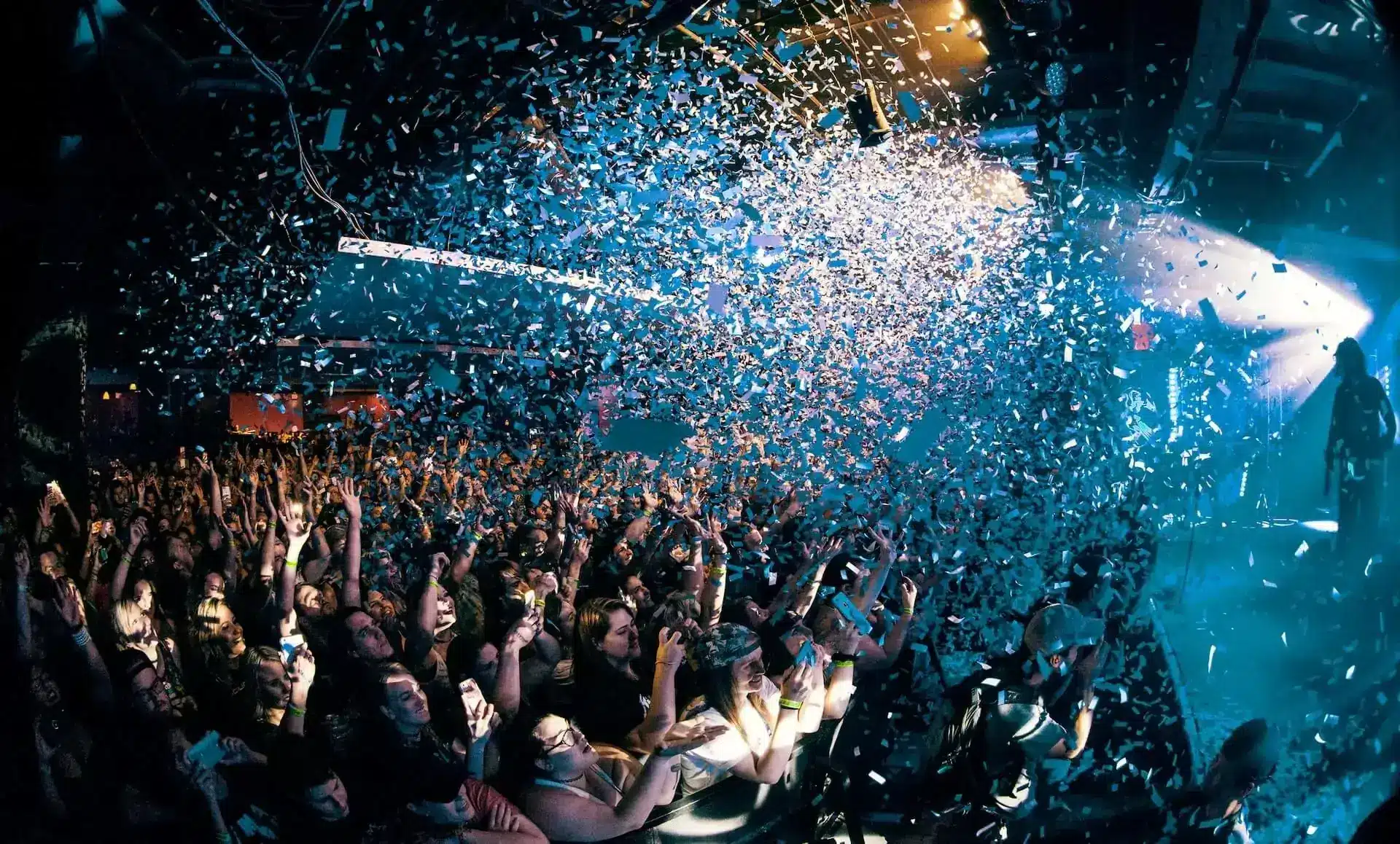Crowd enjoying a confetti drop at a lively event.