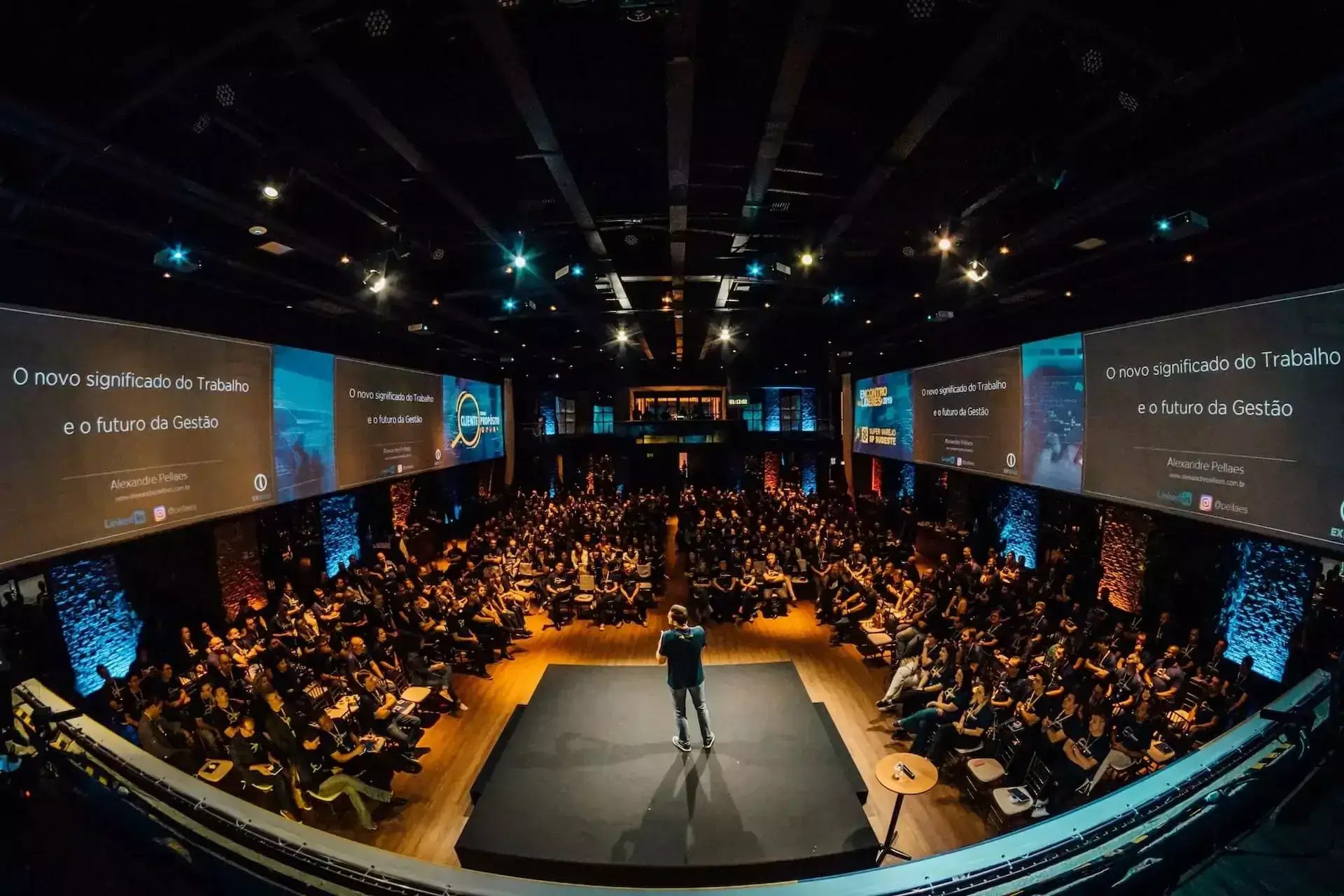 A conference setup featuring stage, audience, and projection screens.
