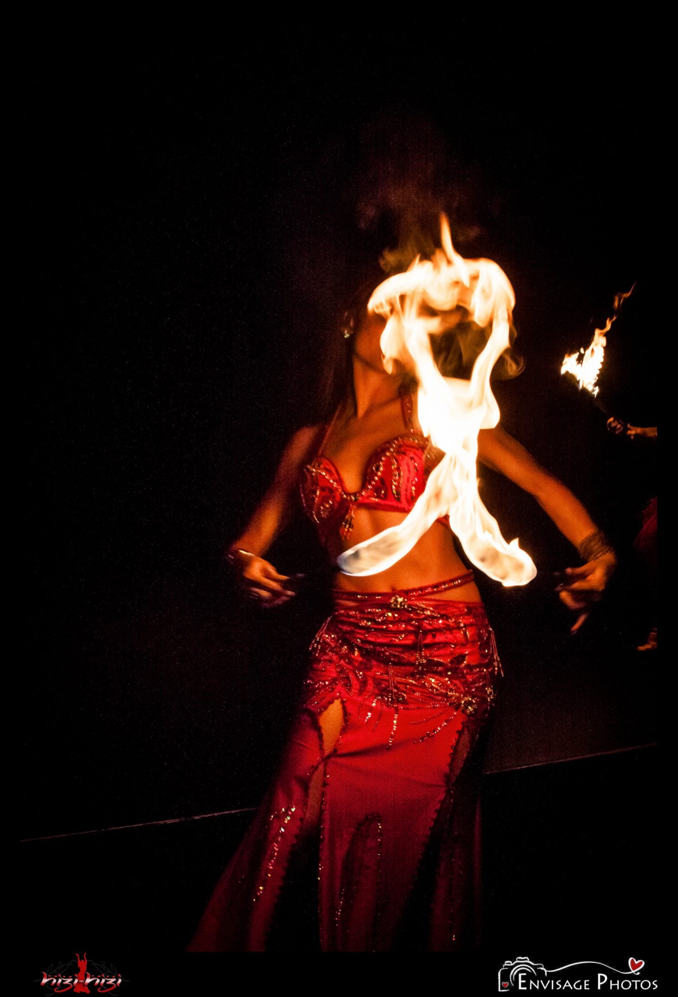 Belly dancer in red costume performing with fire