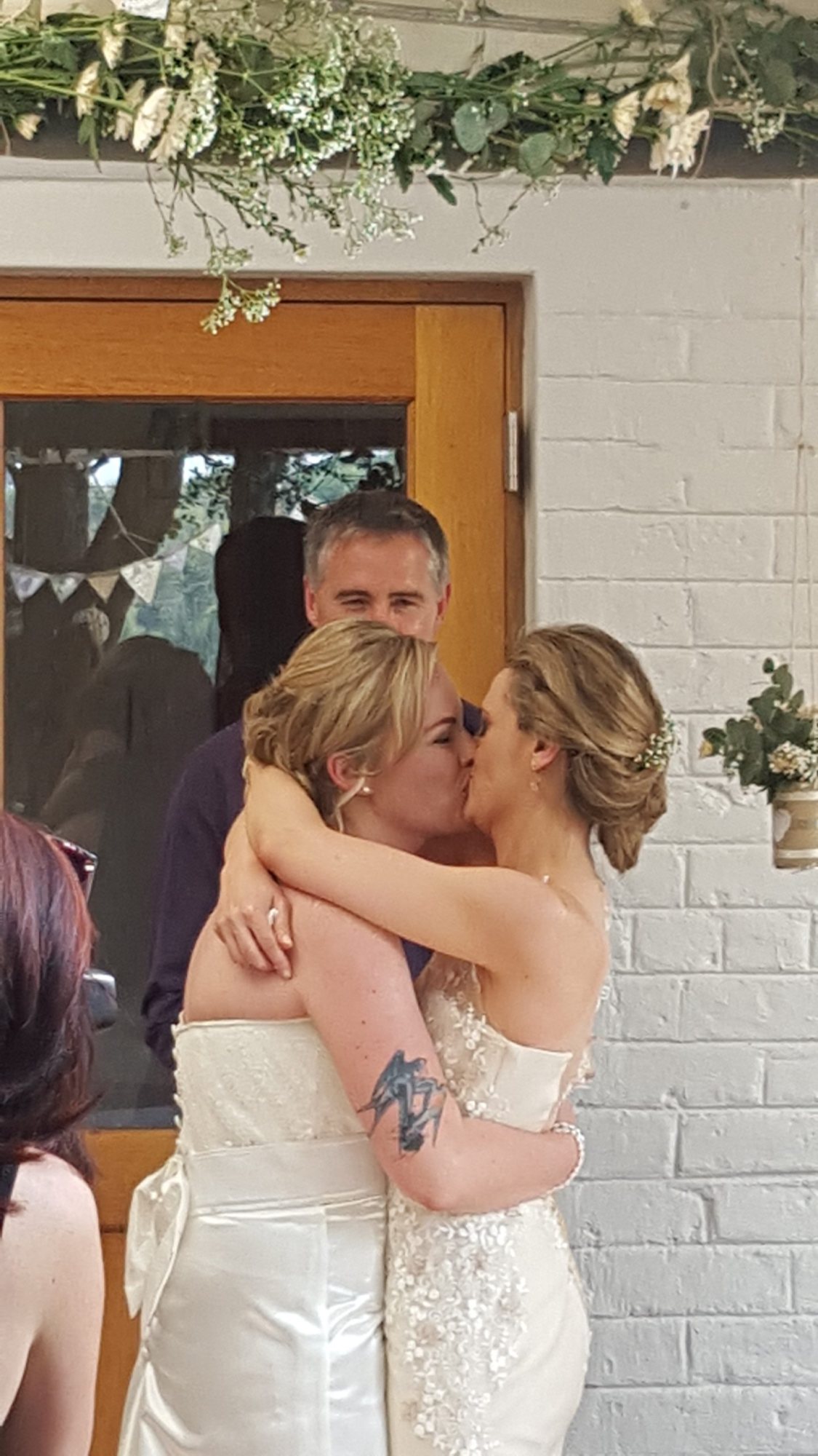 Two brides kissing in a rustic wedding setting