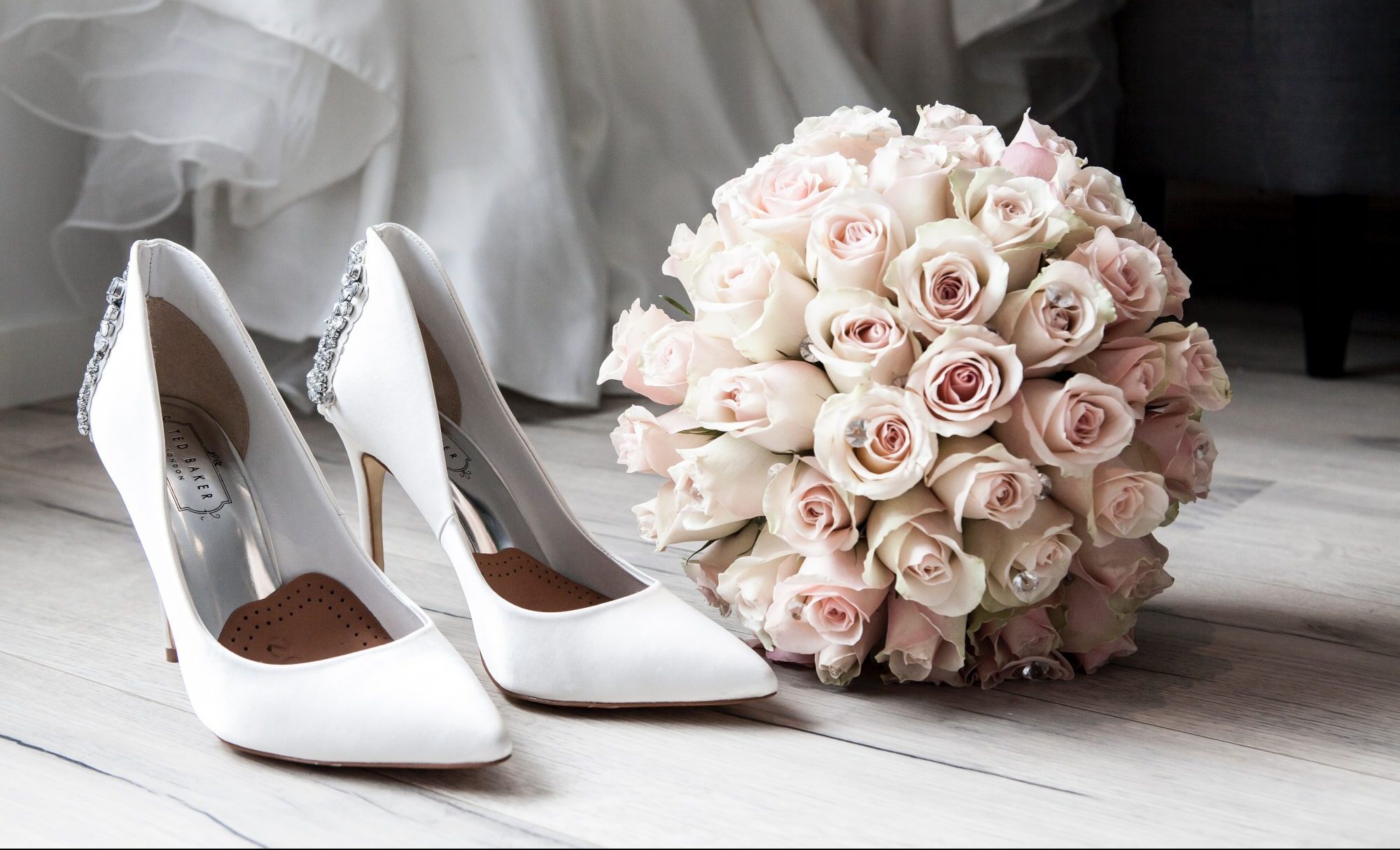 White high-heeled shoes and a pink rose bouquet