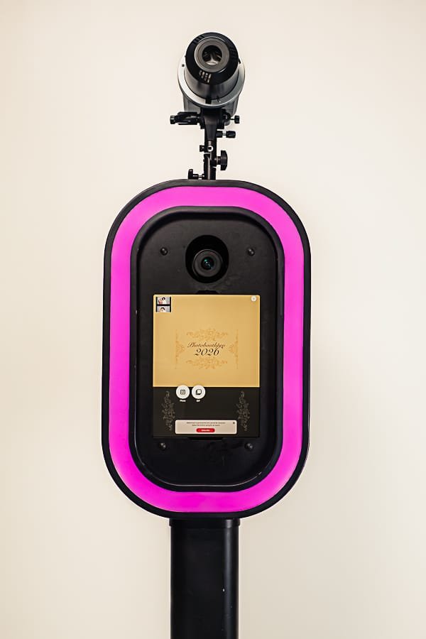 Black magic mirror photo booth with pink trim and camera.
