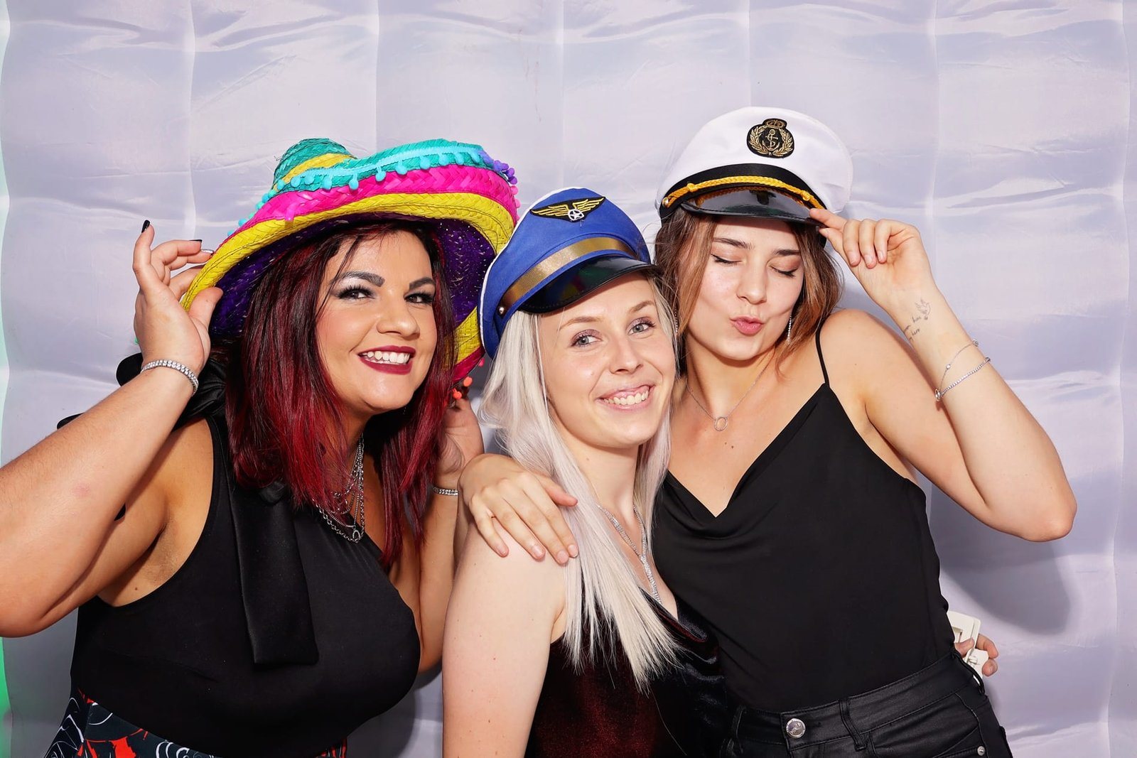 Three women in festive hats smiling together
