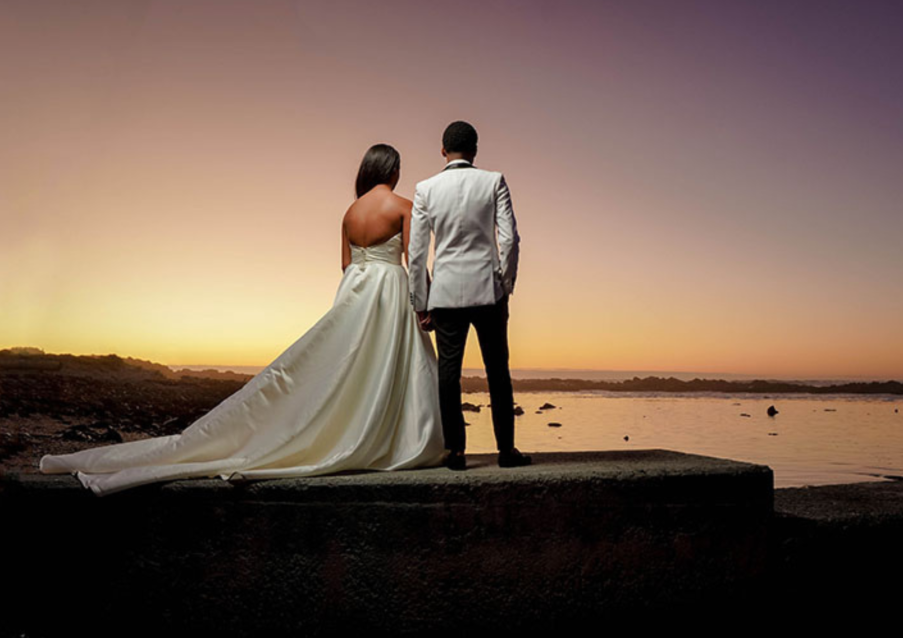 Couple holding hands at sunset near the ocean.