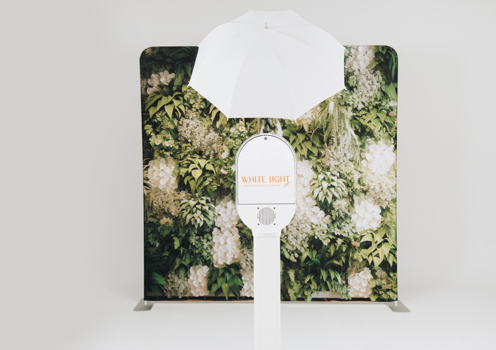 Photo booth with white umbrella and floral backdrop