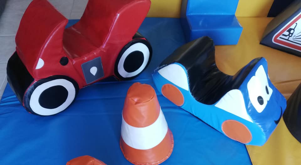 Red and blue soft play cars with a traffic cone