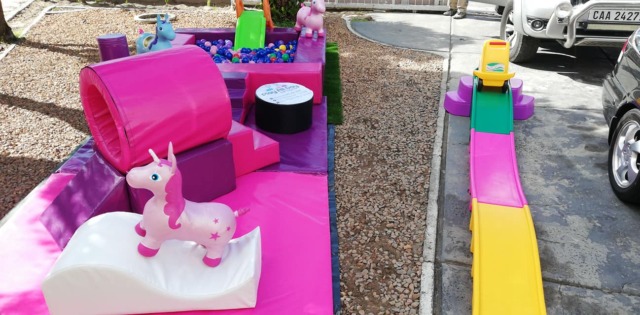 Colorful unicorn-themed soft play area with slide and ball pond