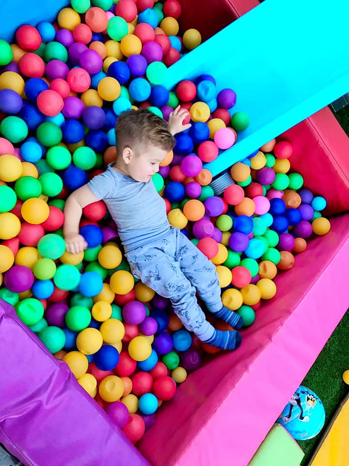 Child lounging in a colorful ball pond