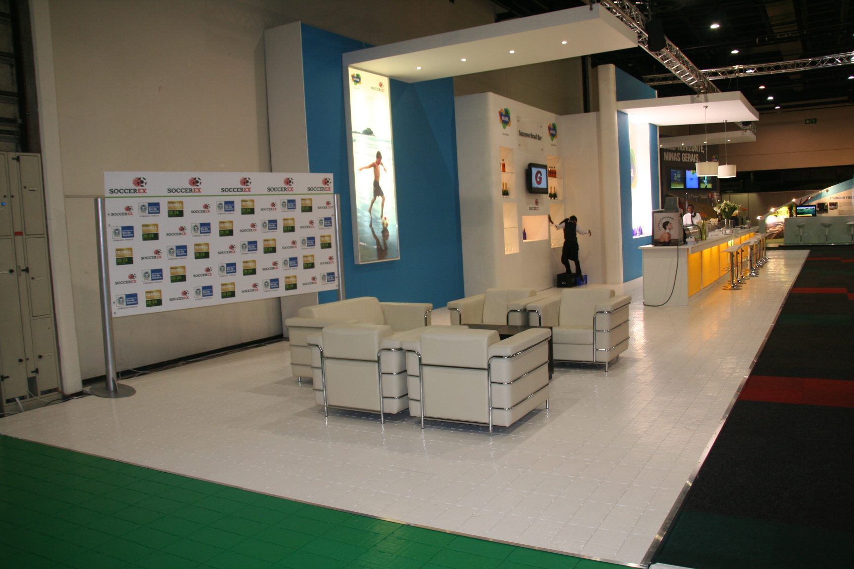 White exhibition flooring with seating area and branding backdrop