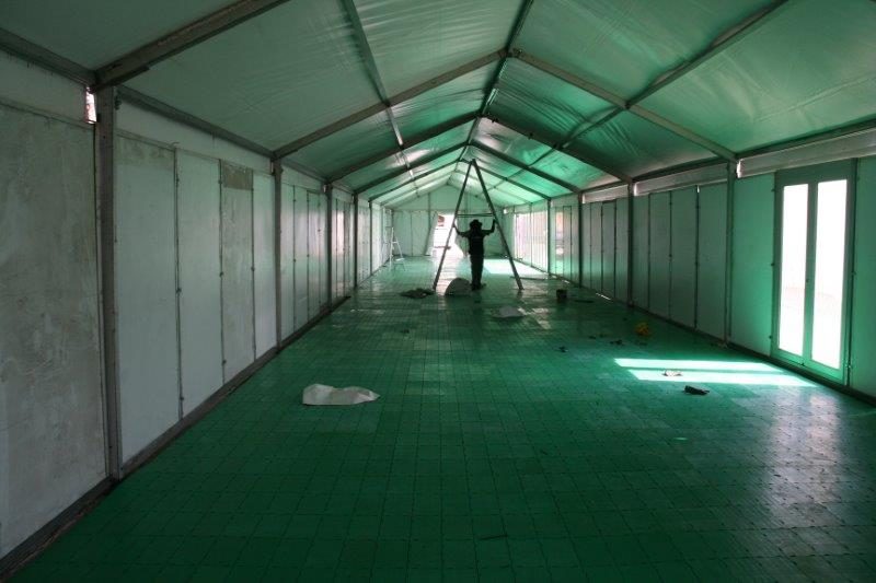 Green portable flooring being installed inside a marquee tent.