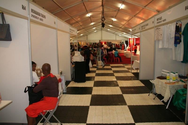 Flooring setup for an exhibition with stalls and attendees in a tent