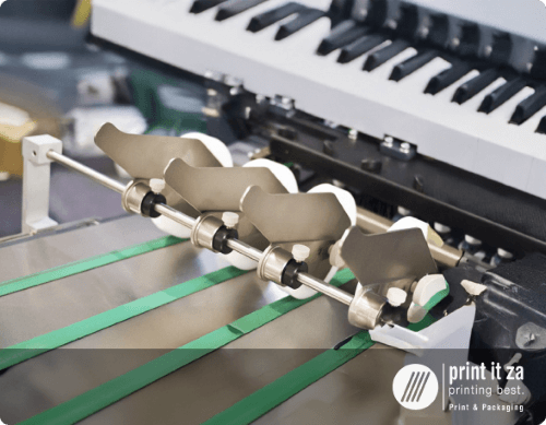 Close-up of printing machinery with rollers and green ink tape
