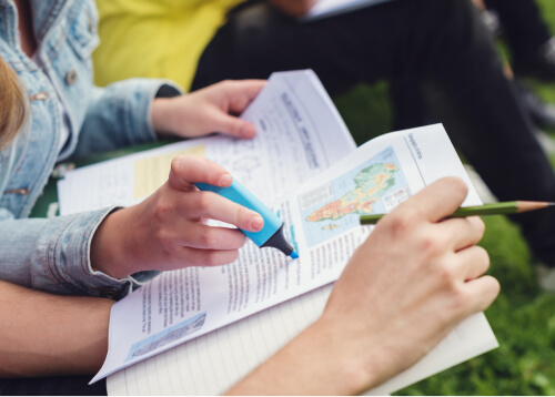 Hands holding open notebooks and highlighting text