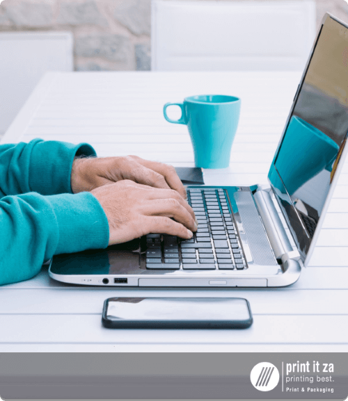 A person typing on a laptop with a coffee cup nearby.