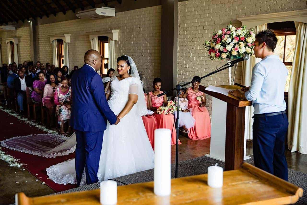 Couple exchanging vows during a wedding ceremony in a decorated venue.