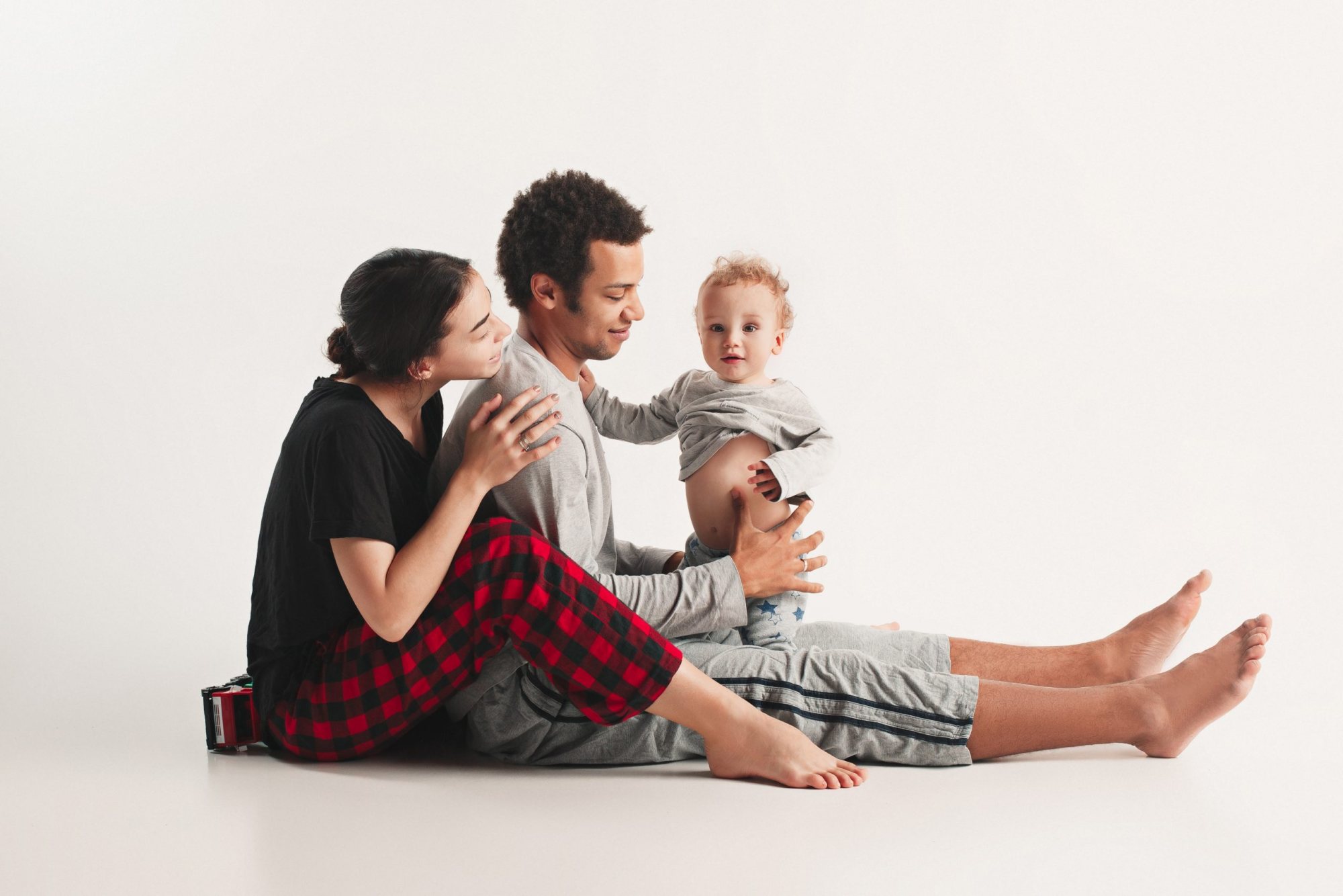 A family of three sitting together on a white background
