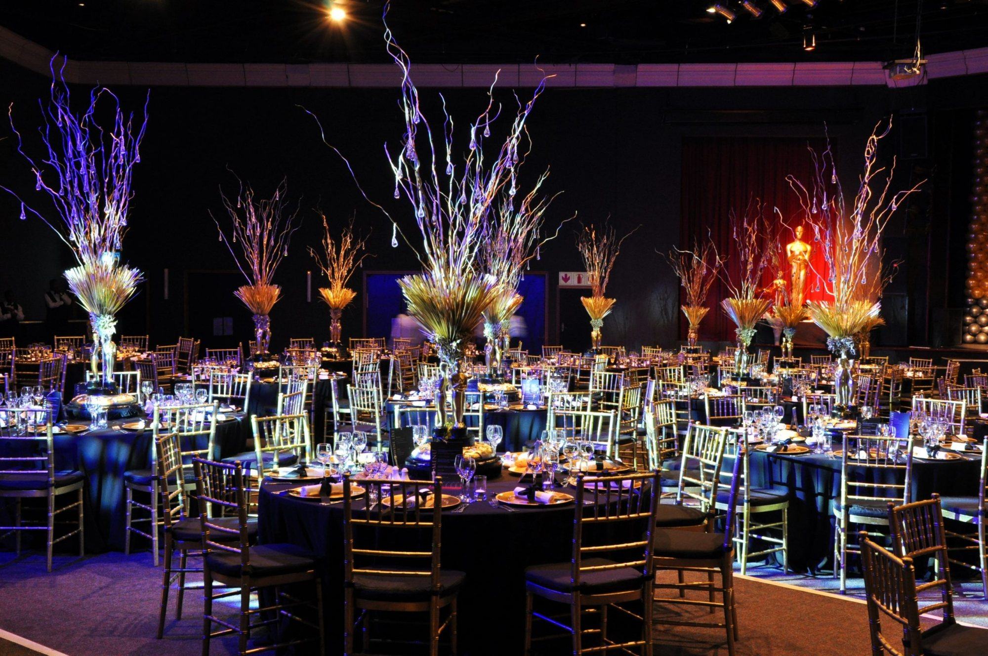 Elegant event setup with gold chairs and artistic centerpieces.