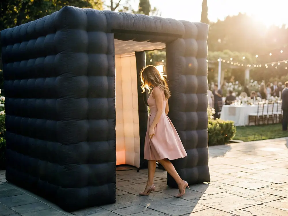 Guest entering a black inflatable photo booth outdoors.