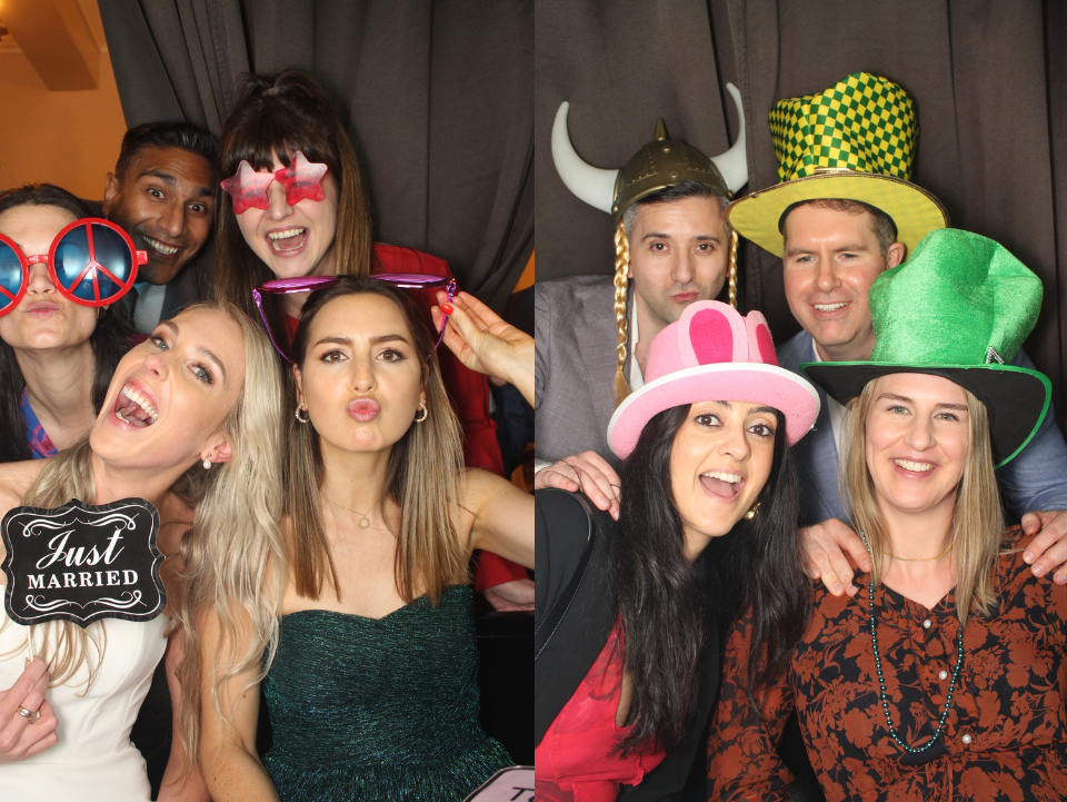 Group of guests posing in a photo booth with fun props