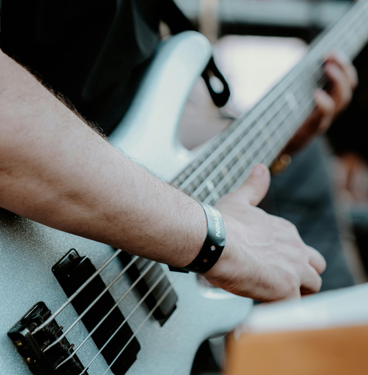 Close-up of a hand playing a silver bass guitar.