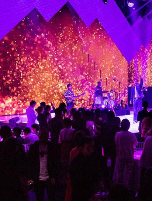 Musicians on stage with colorful lights and audience