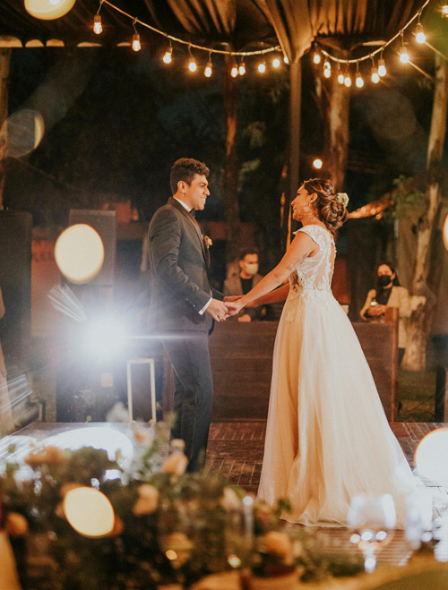 Couple dancing under string lights in an outdoor venue.