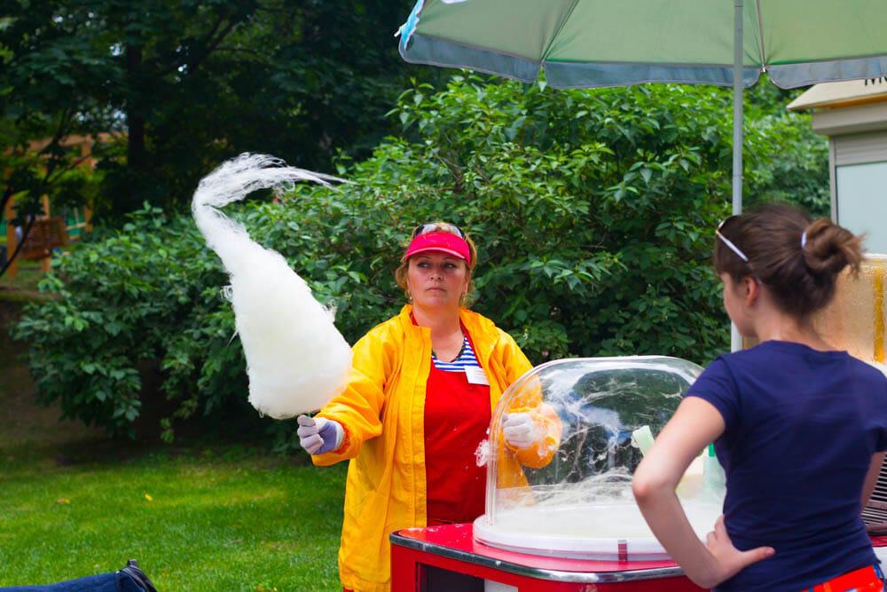 Person serving candy floss with a machine in a garden setting.