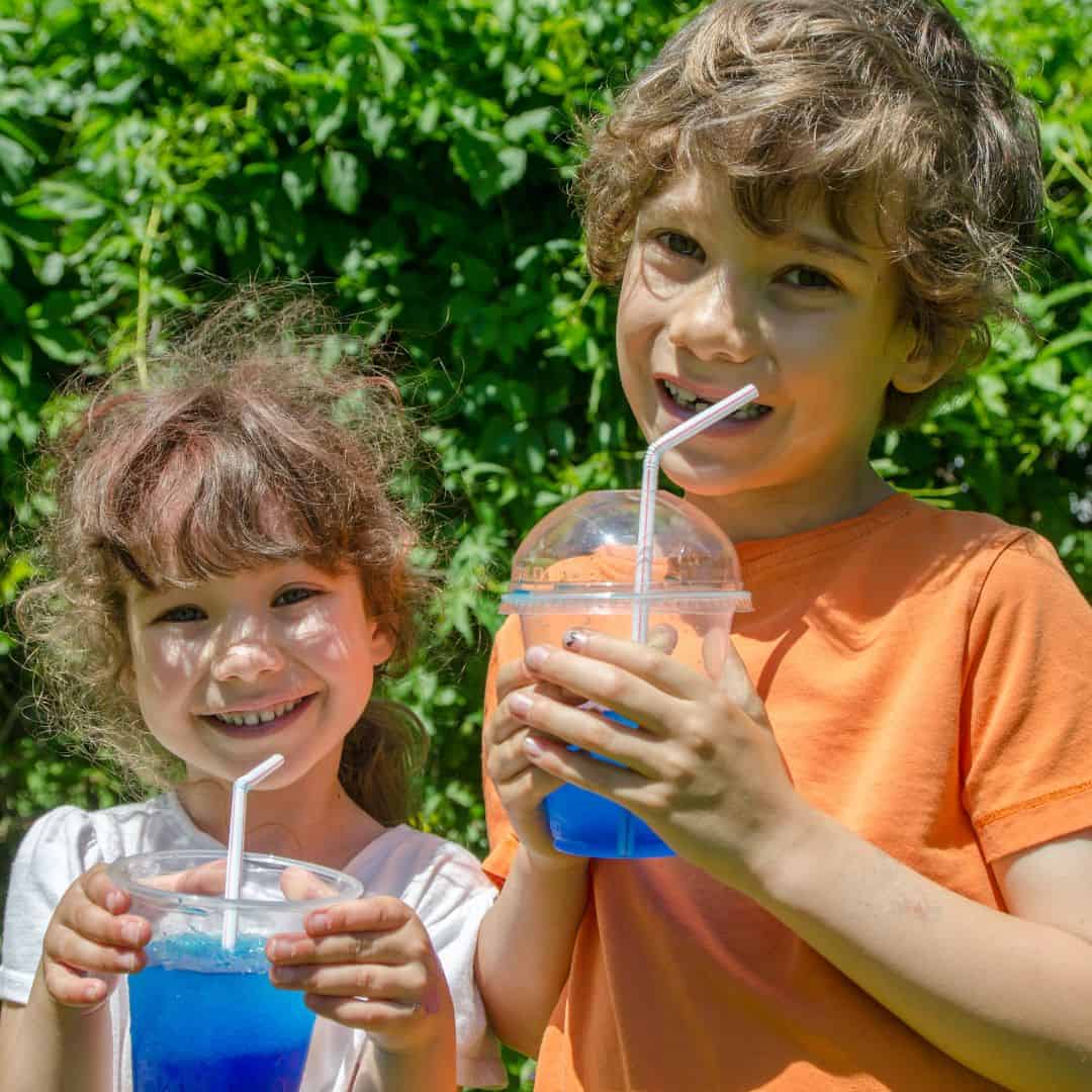 Two children holding slushy drinks with bright blue colors