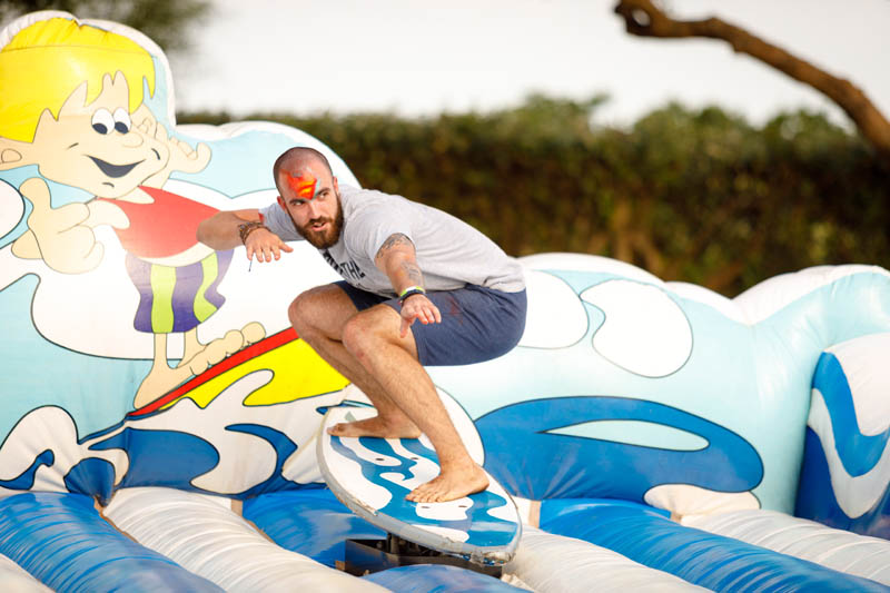 Person riding a mechanical bull on a water-themed inflatable