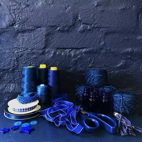 Collection of blue threads, ribbons, and crafting supplies on a dark background