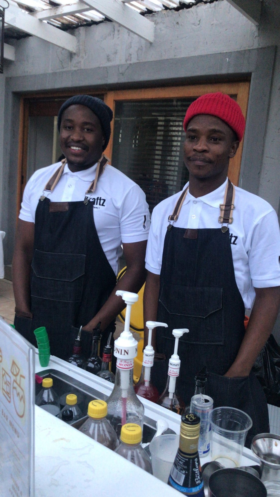 Two bartenders in aprons at a mobile bar.