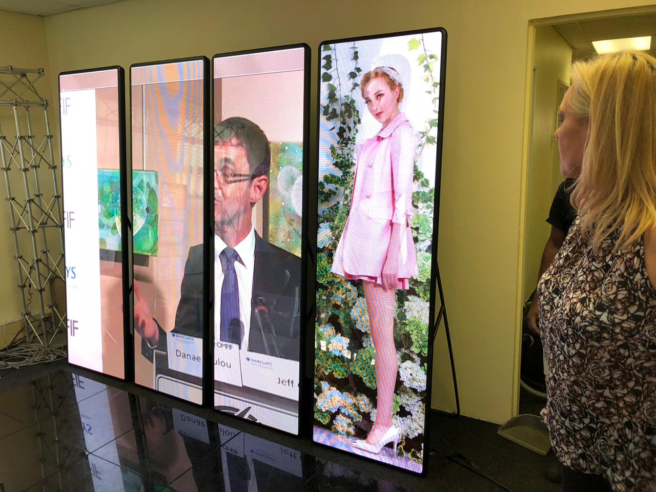 Modular LED displays set up in a venue with a speaker and model.