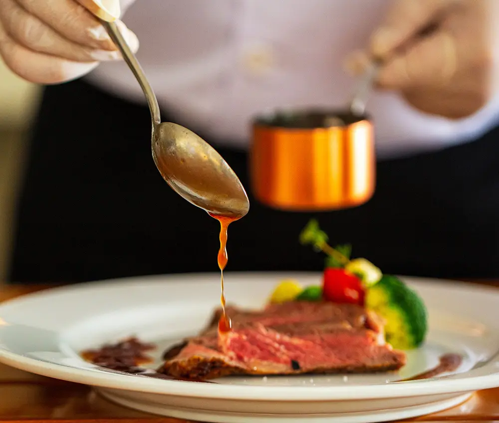Chef adding sauce to a plated gourmet dish