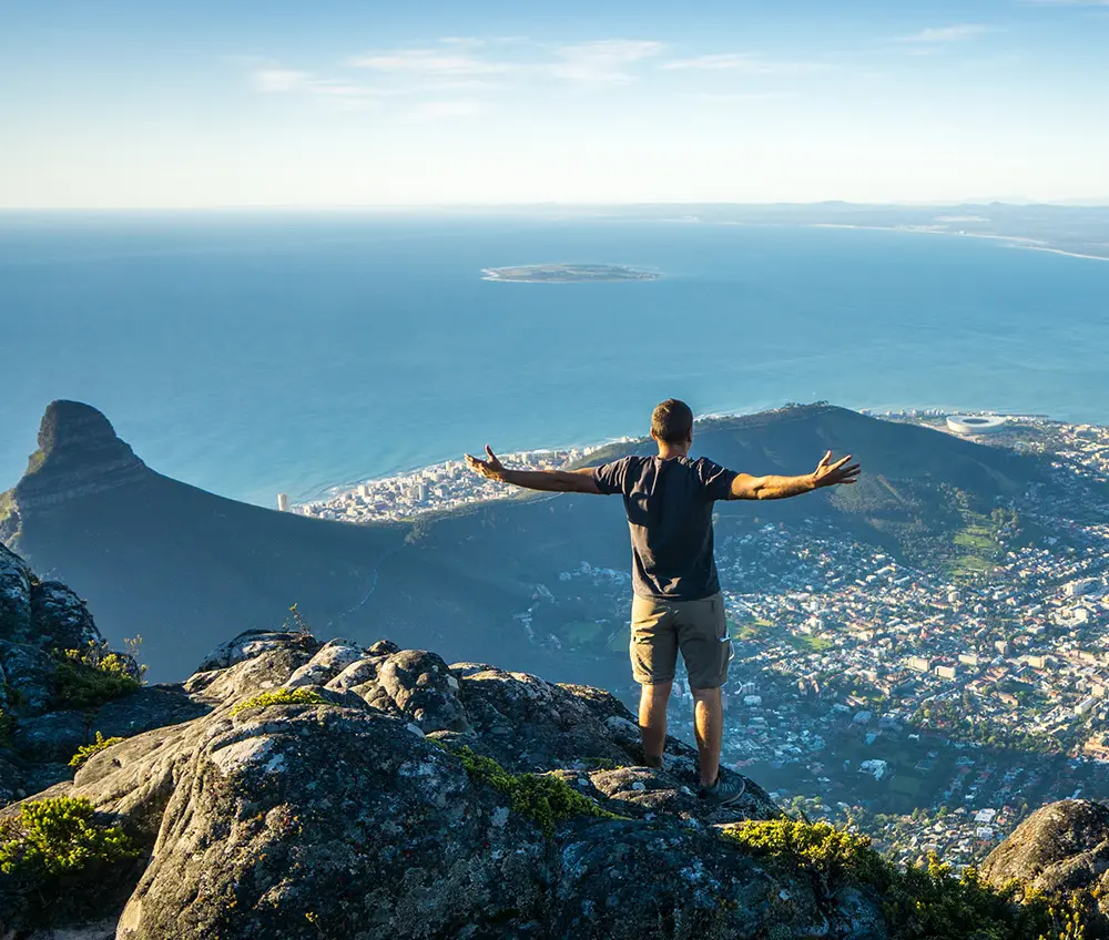 Man standing on a mountain overlooking Cape Town