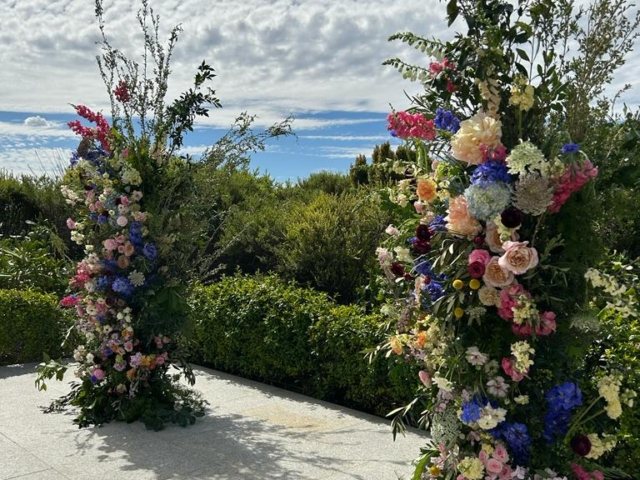 Two tall floral arrangements with mixed flowers outdoors